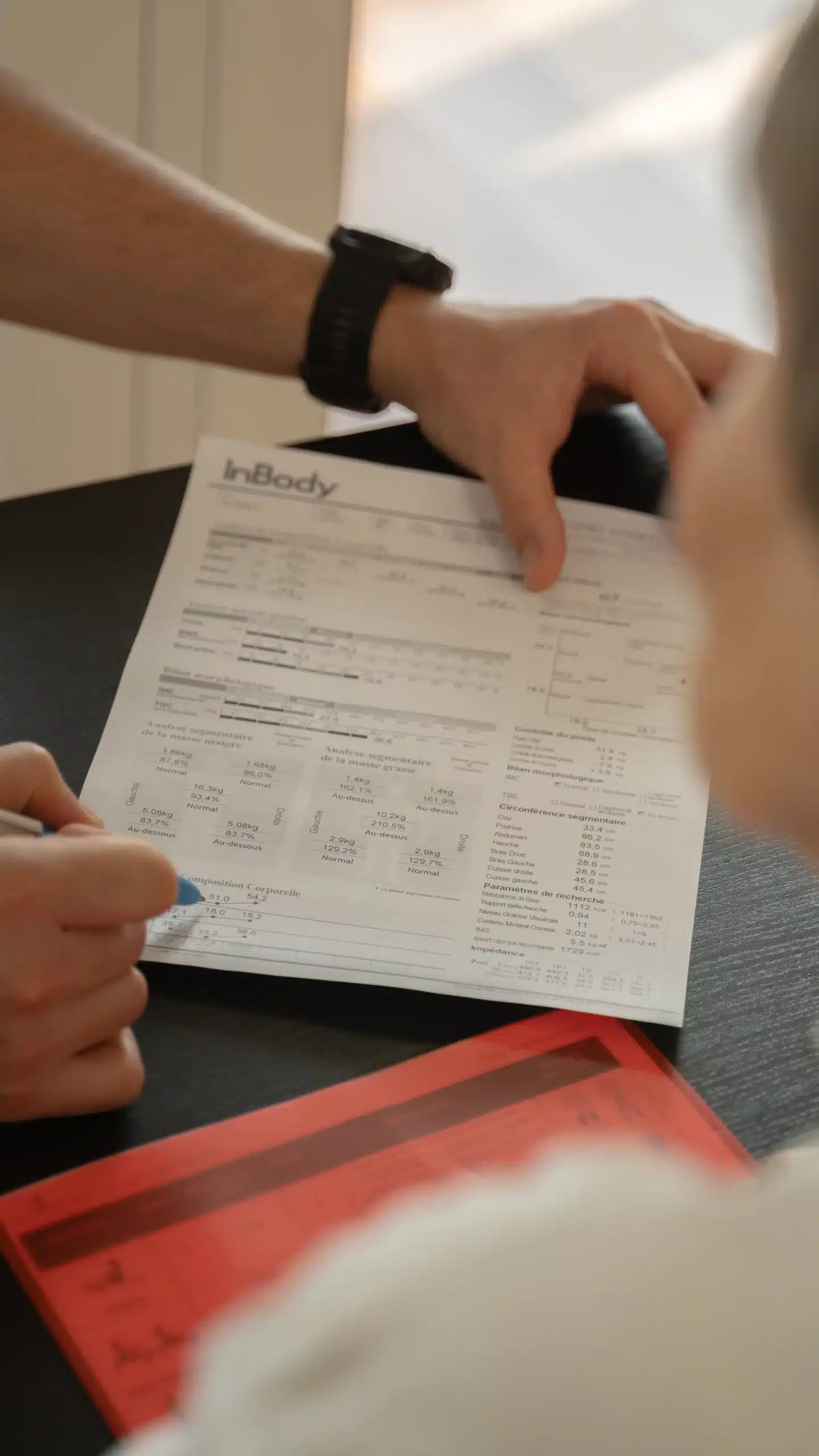 Consultation InBody : un coach analyse les résultats de composition corporelle (masse maigre, IMC, métabolisme de base) avec un client.